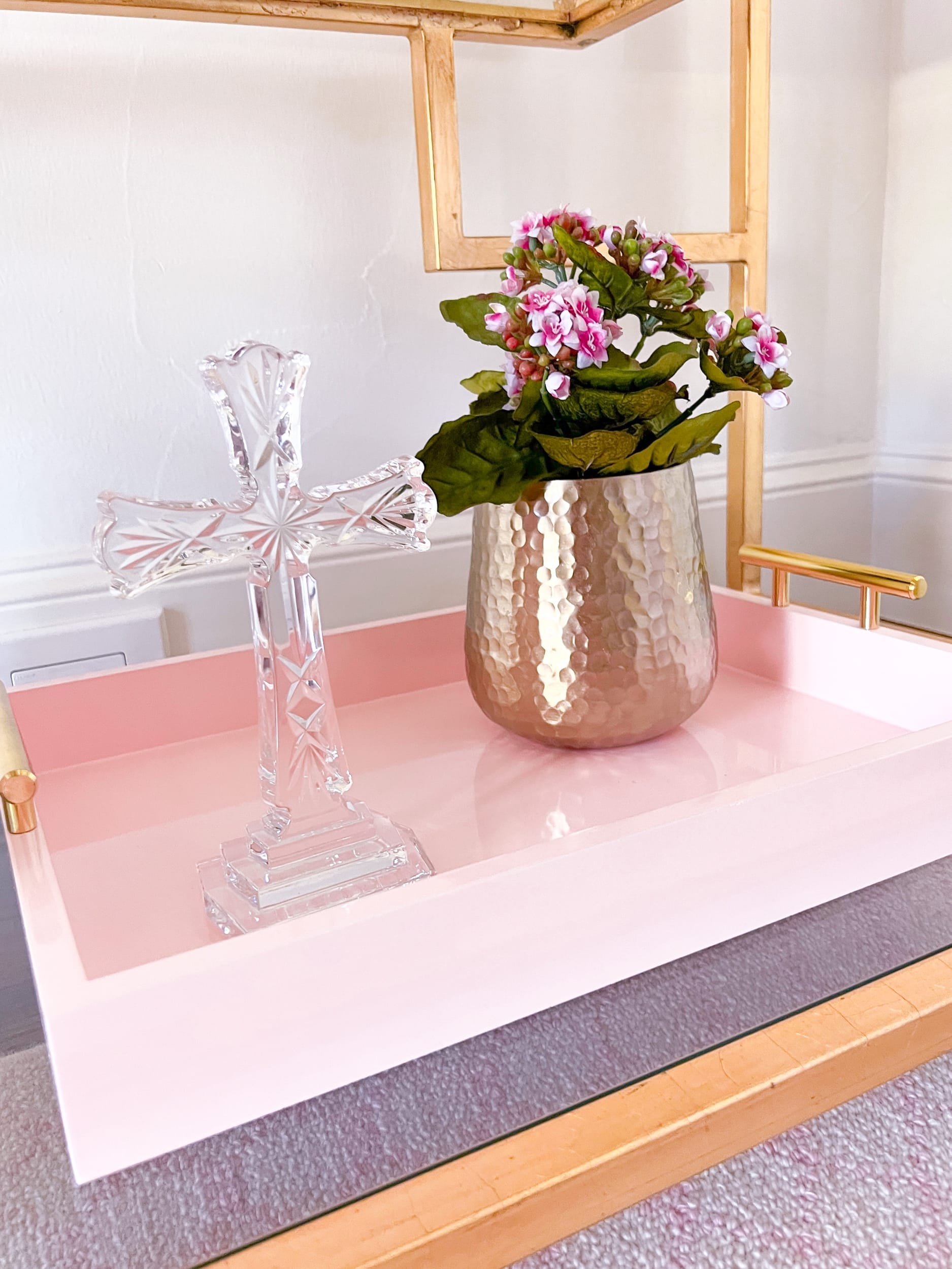 pink wooden tray with crystal cross and faux flowers on it