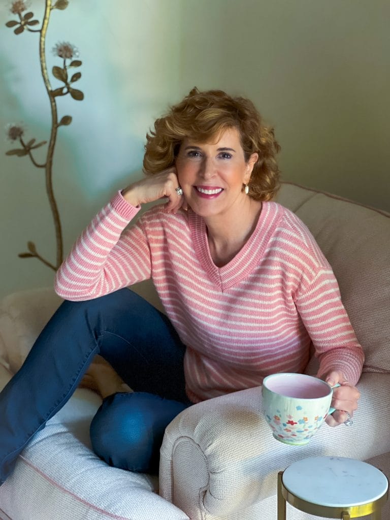 woman holding a cup of coffee sitting in a chair and looking at the camera talking about having meaningful conversations with adult kids