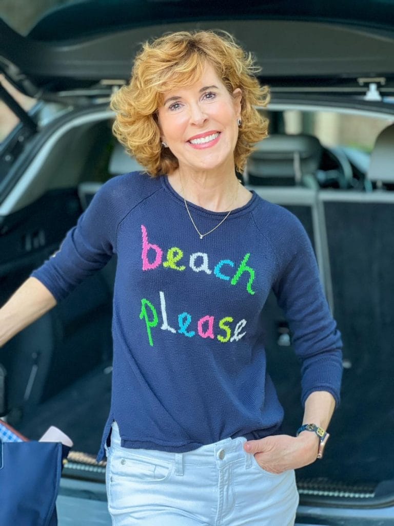 woman standing by the trunk of a car wearing a lilly pulitzer beach please sweater