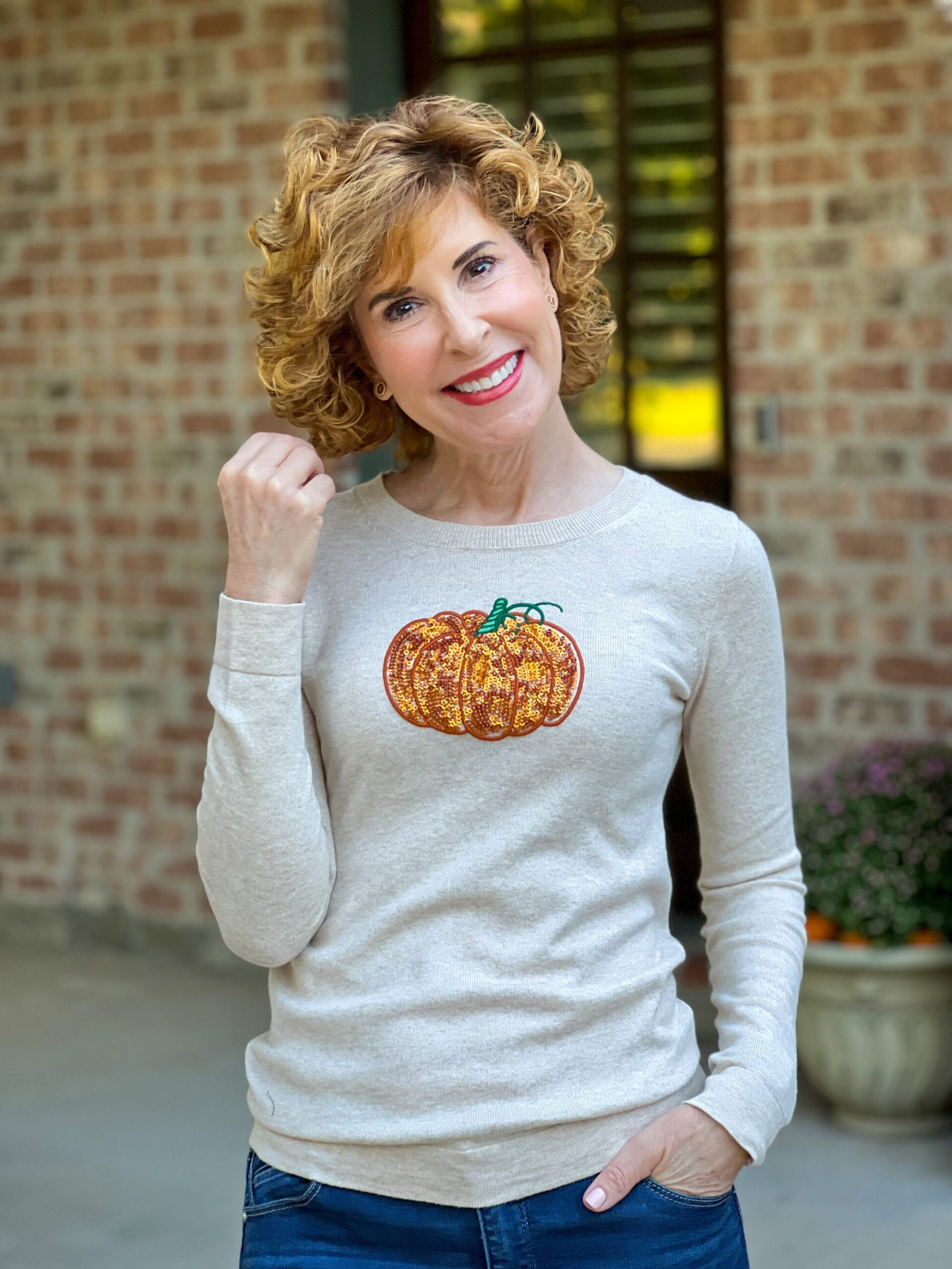 woman over 50 standing on her back porch wearing a j.Crew factory sequin pumpkin sweater