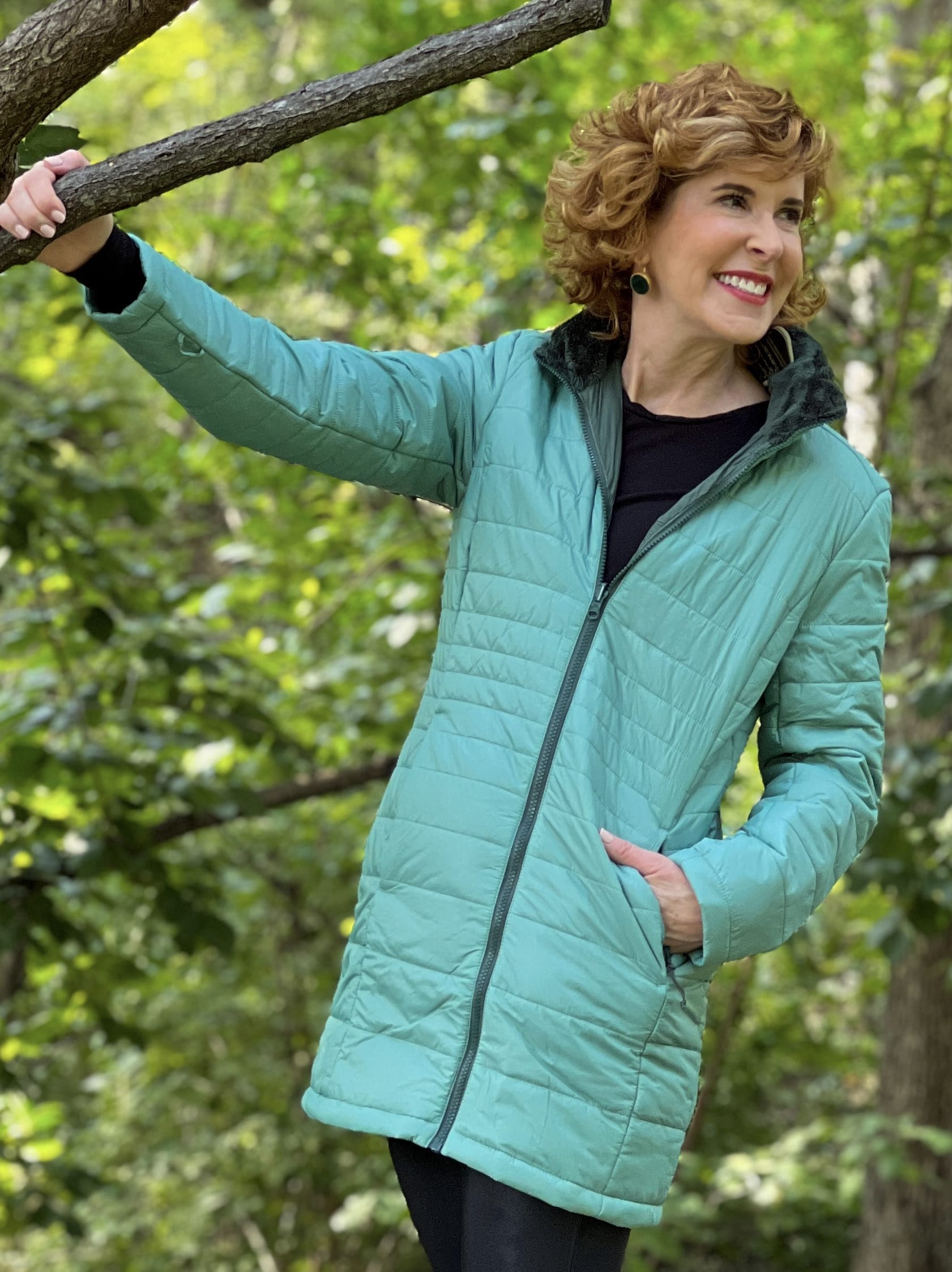 woman wearing green land's end Women's Insulated 3 in 1 Primaloft Parka - puffer part and black leggings standing on a bridge in the park