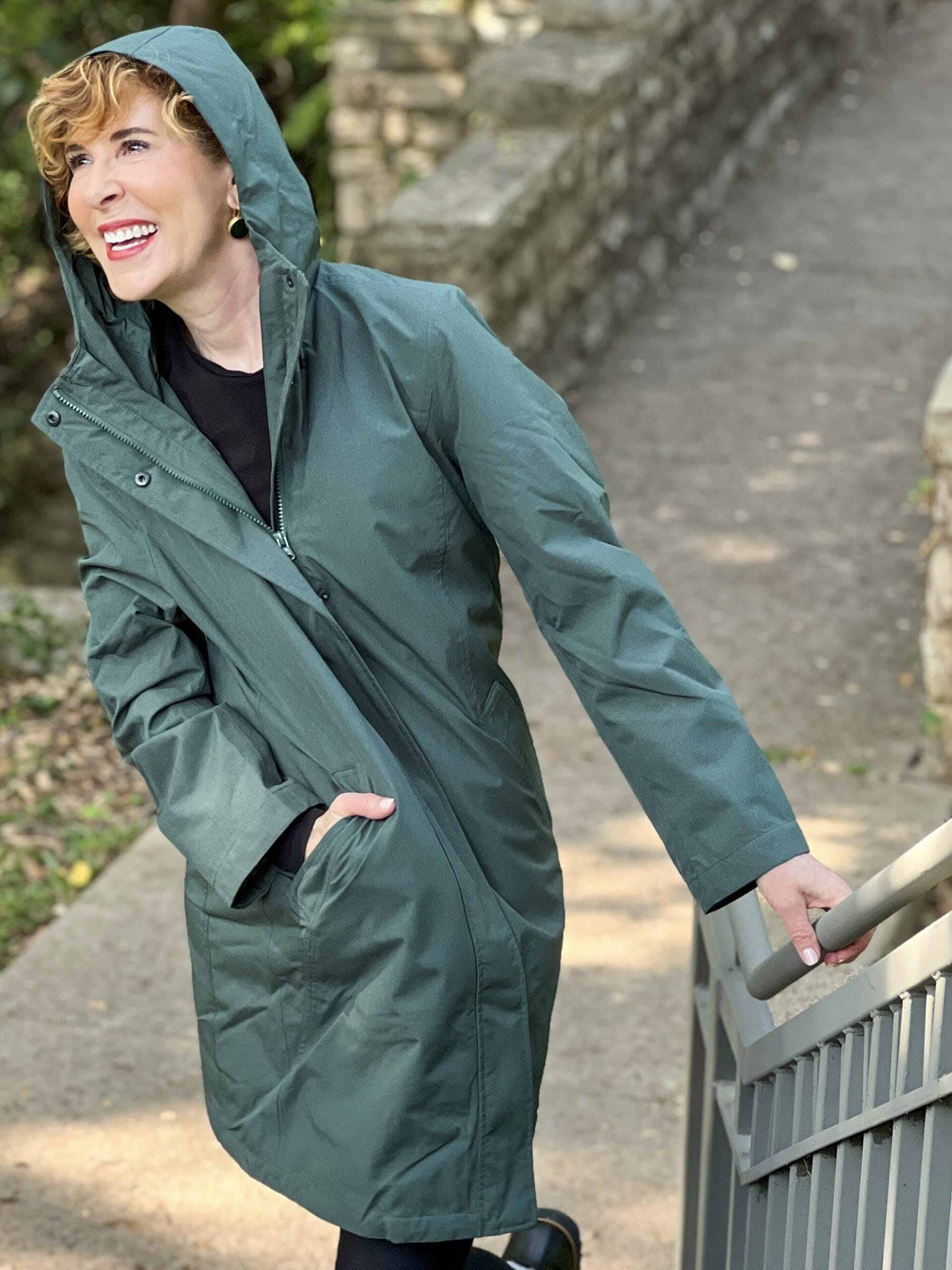 woman wearing green land's end Women's Insulated 3 in 1 Primaloft Parka – outer rain coat part - and black leggings standing by a staircase in the park