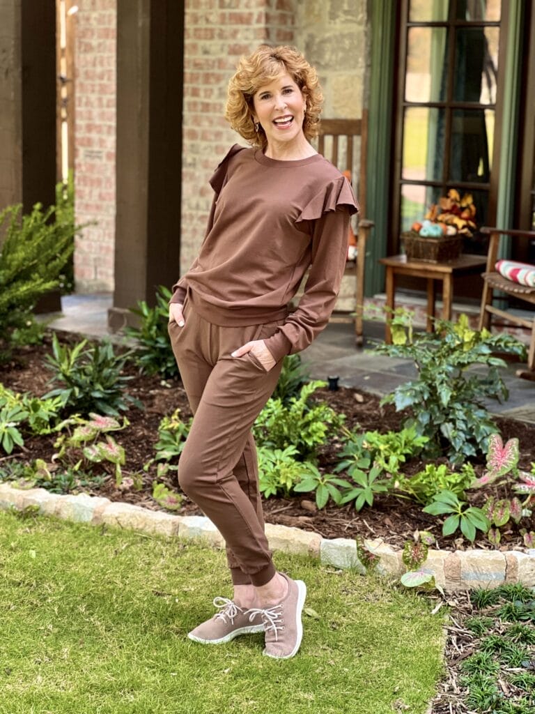 woman wearing two piece brown loungewear set standing in front yard