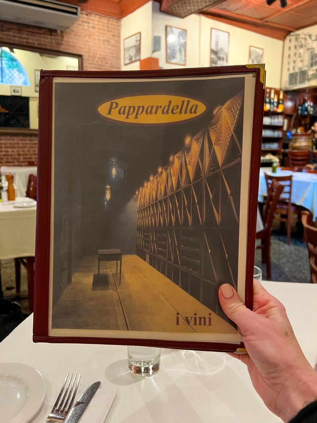 woman's hand holding up a menu from pappardella restaurant in nyc