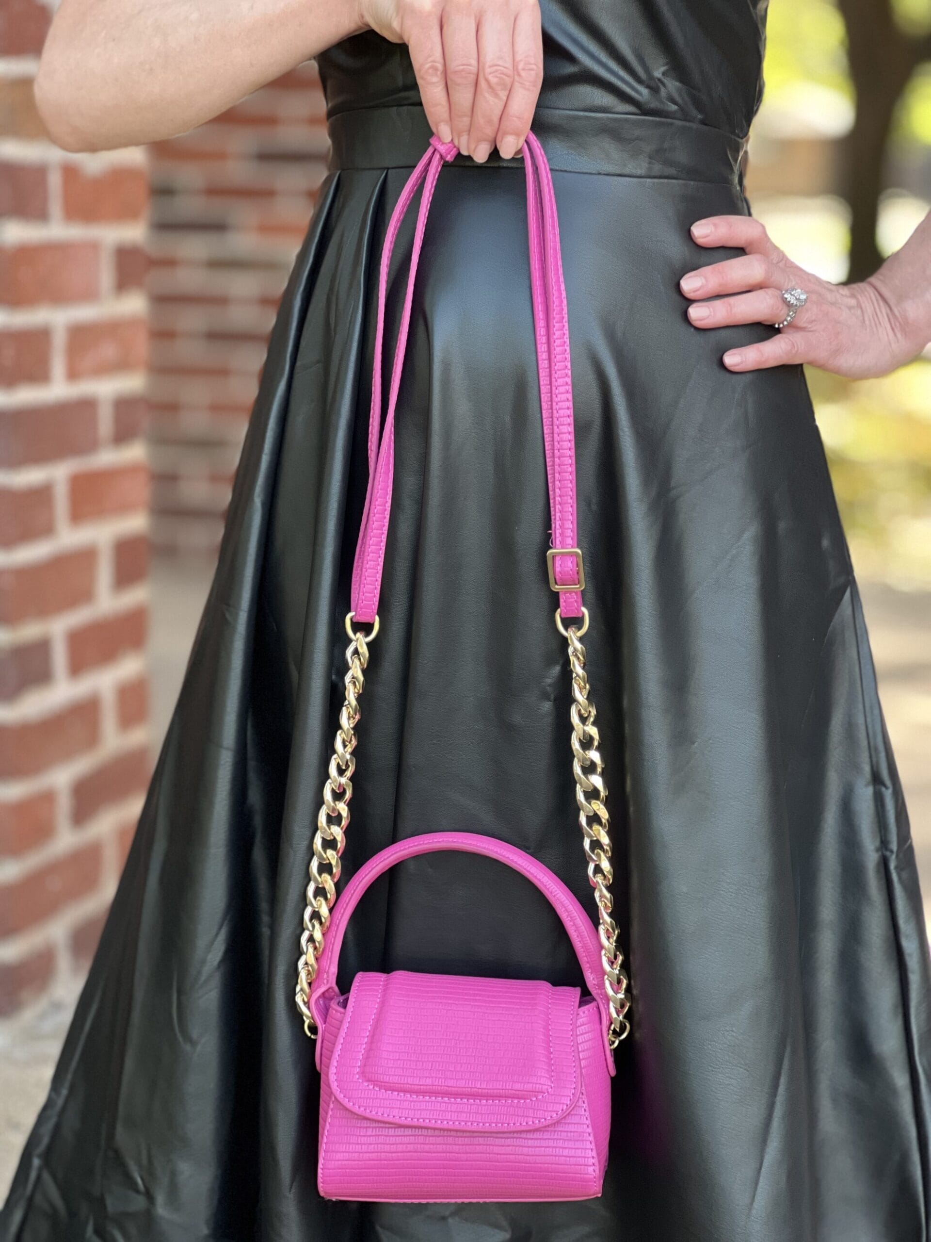 woman holding Scoop Women's Mini Structured Bag in rose violet from Walmart against a black faux leather dress