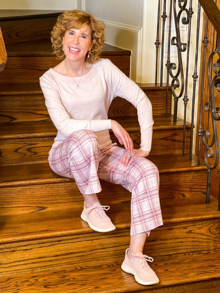 woman over 50 sitting on staircase wearing playdate crop, ballet sweater, lagoon necklace, lagoon earrings and pink sneakers