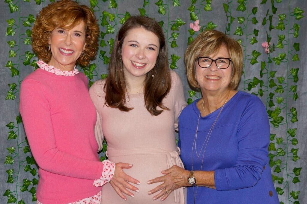 Two women resting their hands on a pregnant woman's stomach