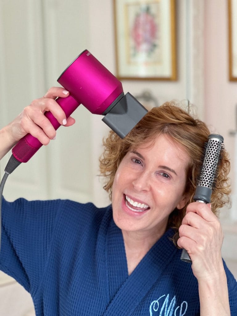 woman over 50 styling her hair with a blow dryer