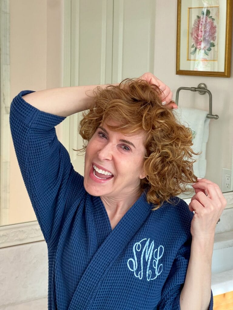 woman in blue monogrammed robe showing her curly hair before washing