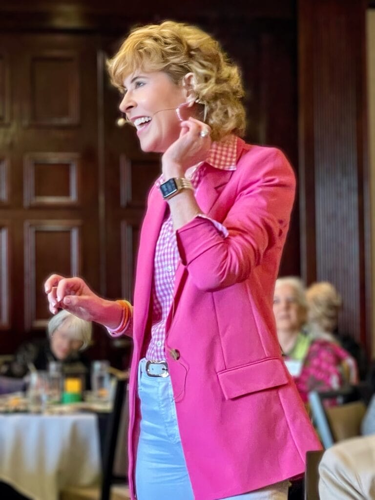 Woman over 50 wearing pink blazer speaking to a group