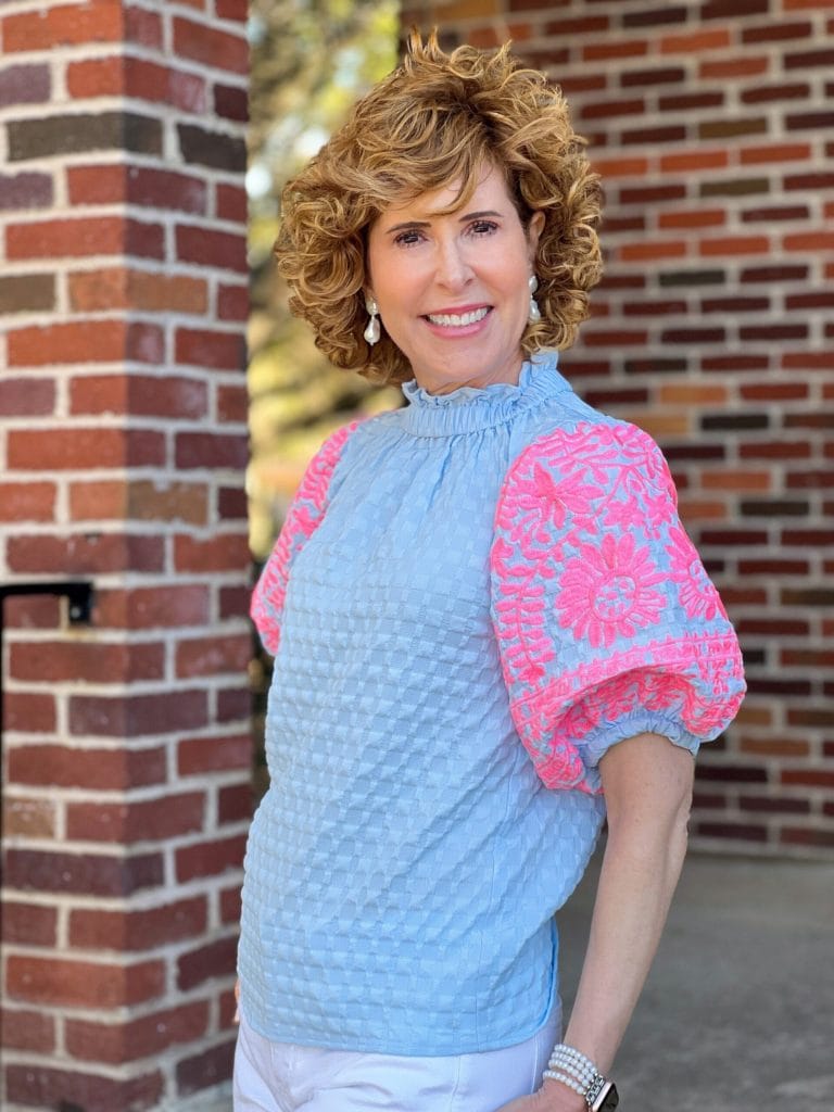 woman over 50 standing by brick wall wearing avara lina top