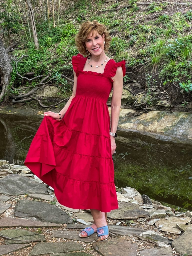 woman wearing hill house home nap dress in red with flag sandals standing by a stream
