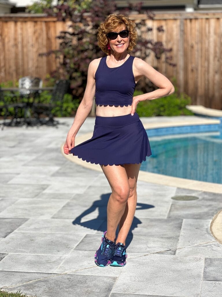 woman over 50 wearing navy blue scalloped workout set standing by a pool wearing amazon workout outfit