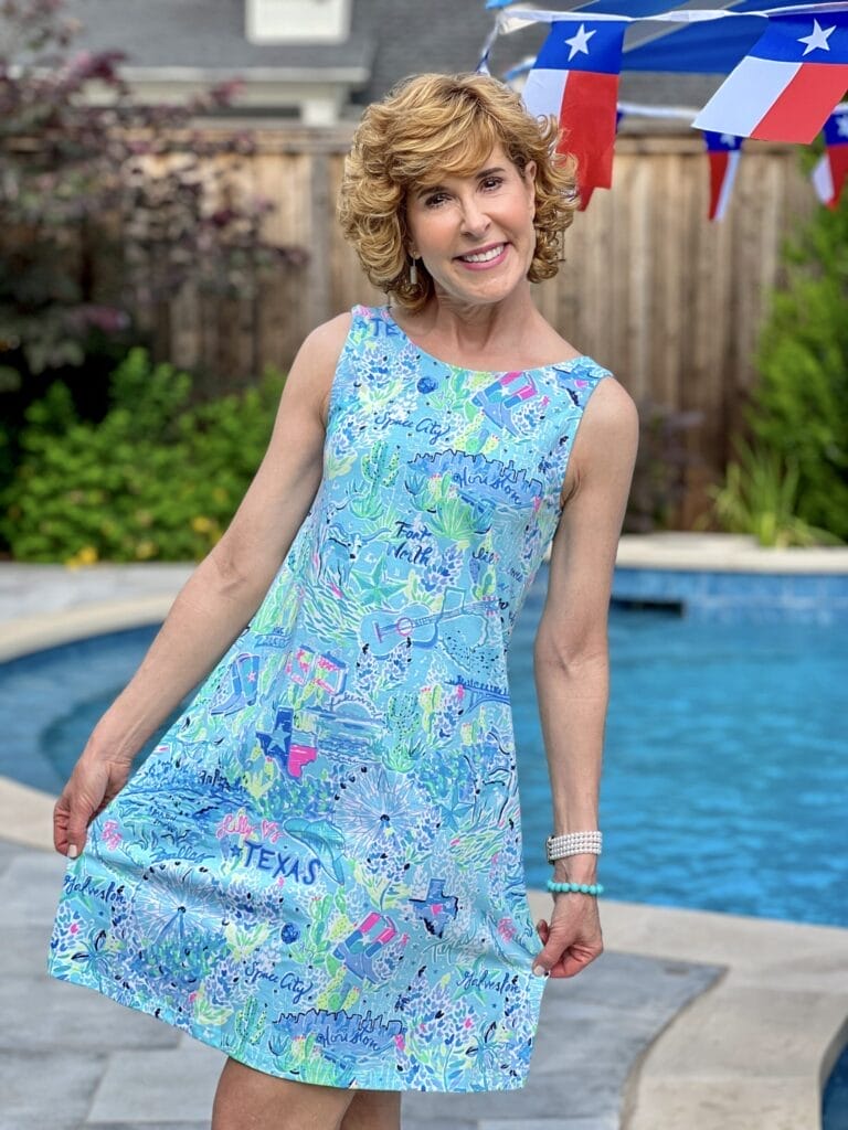 woman wearing lilly pulitzer texas dress standing by a swimming pool