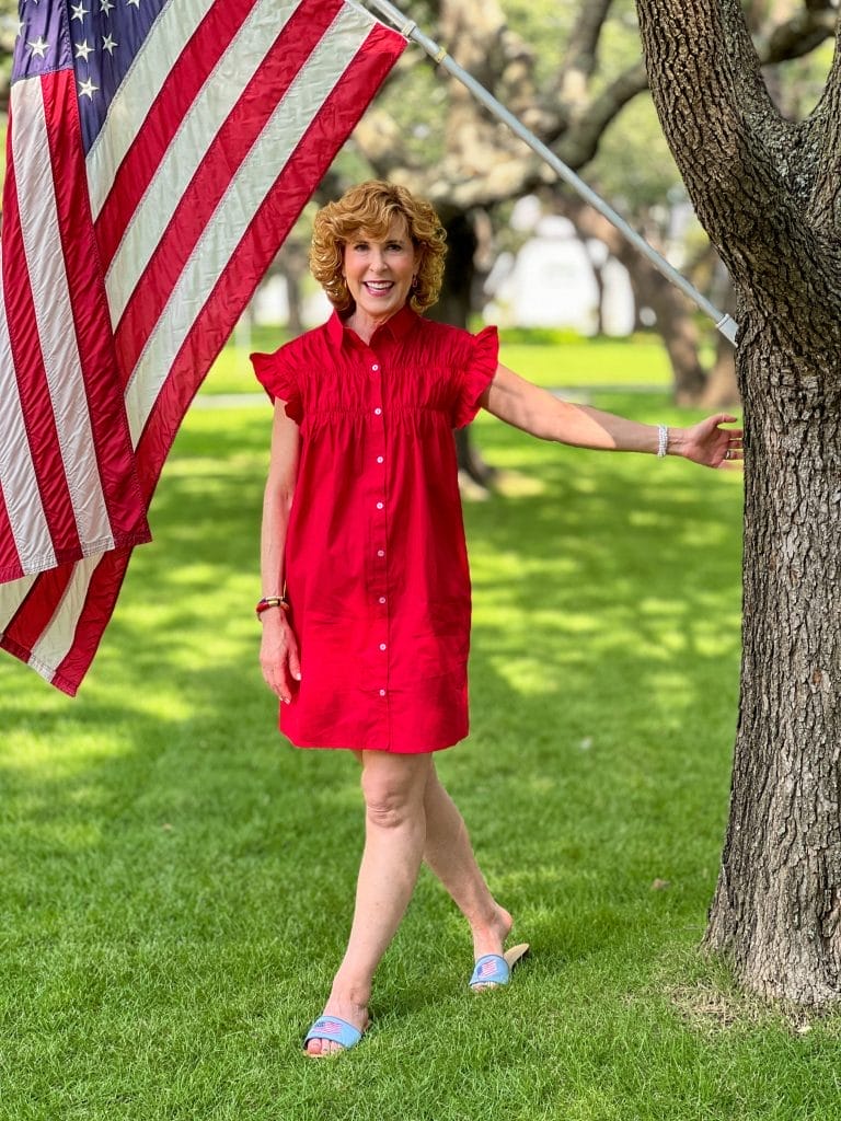 woman wearing red dress in front yard standing by american flag