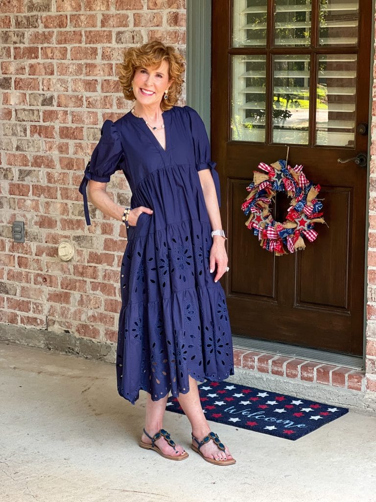 woman wearing navy blue dress with eyelet skirt standing on porch