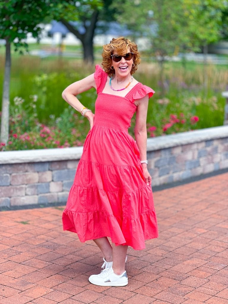 womanstanding on brick patio wearing coral dress