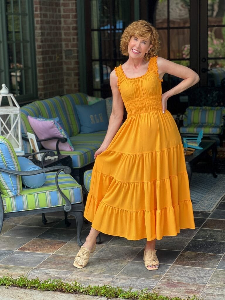 woman over 50 standing on back porch with one leg stretched out wearing Antonio Melani Bentley Square Neck Pebble Crepe A-Line dress from Dillards