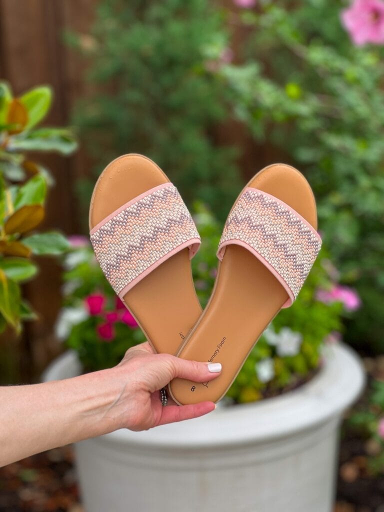 woman's hand holding Time and Tru Women's Core Slide Sandal in front of a flower pot