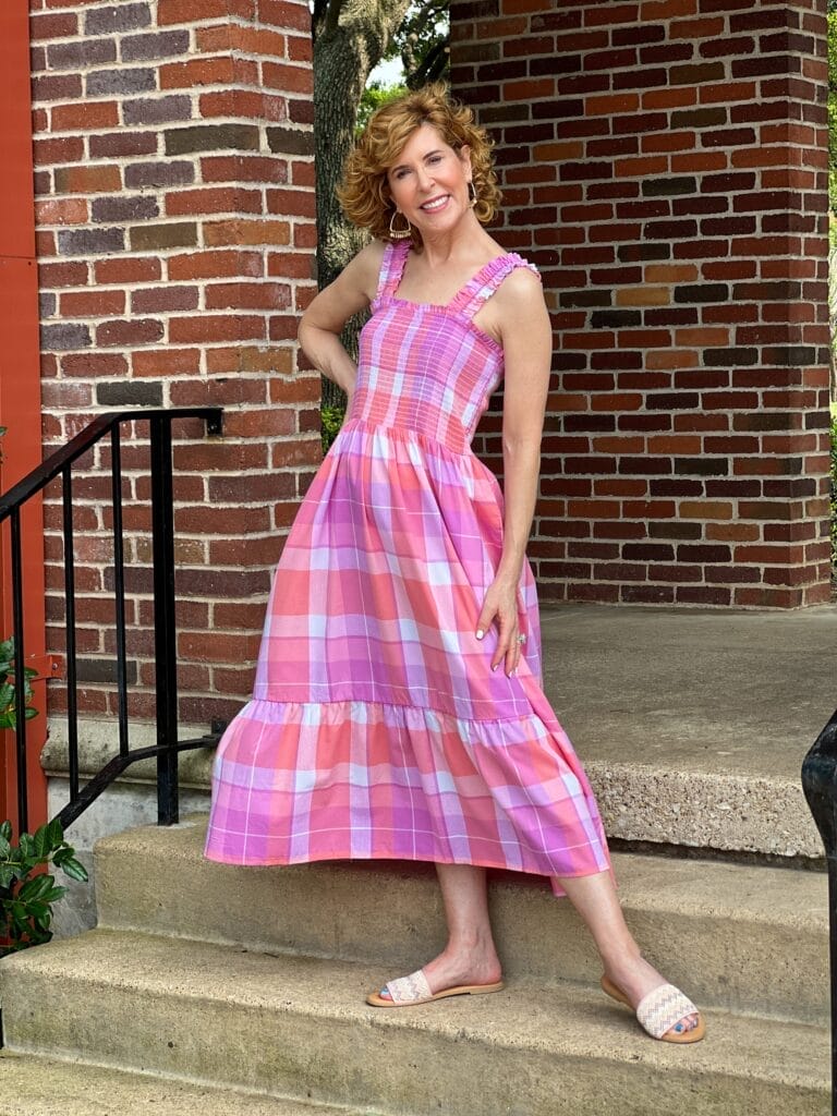 woman standing on stairs outdoors wearing Time and Tru Women's Smocked Midi Dress with Ruffle Straps from Walmart in pink madras plaid
