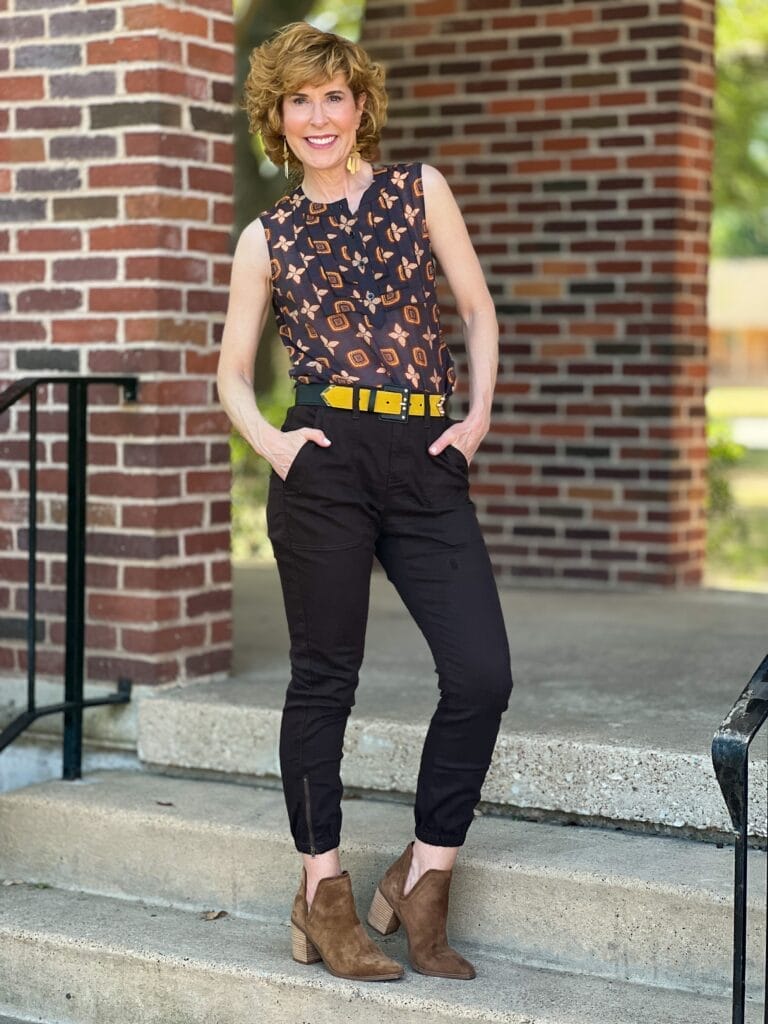 woman standing on stairs wearing cabi louis top and compass pant with hands in her pockets