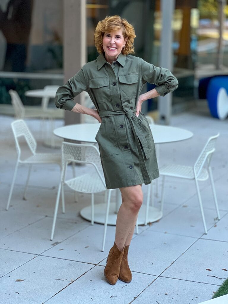 woman wearing fall dress in army green standing by white table and chairs