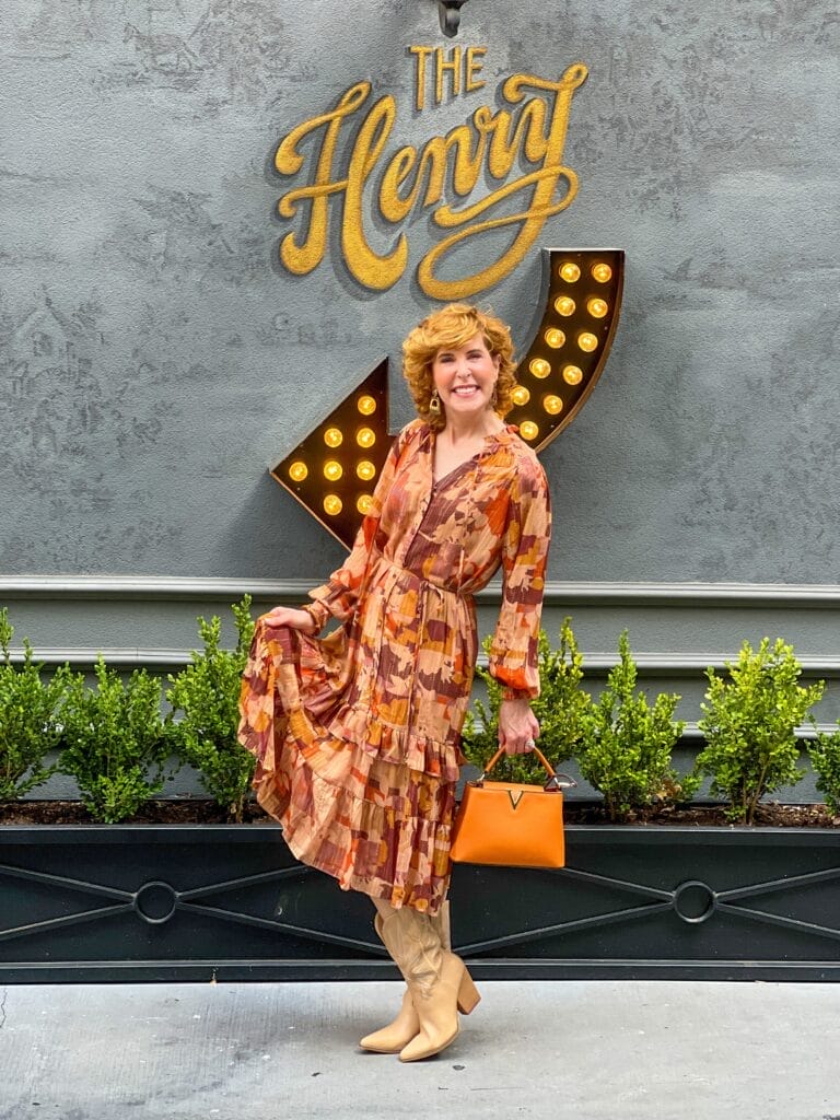 woman posing in front of the henry restaurant wearing a fall dress and boots