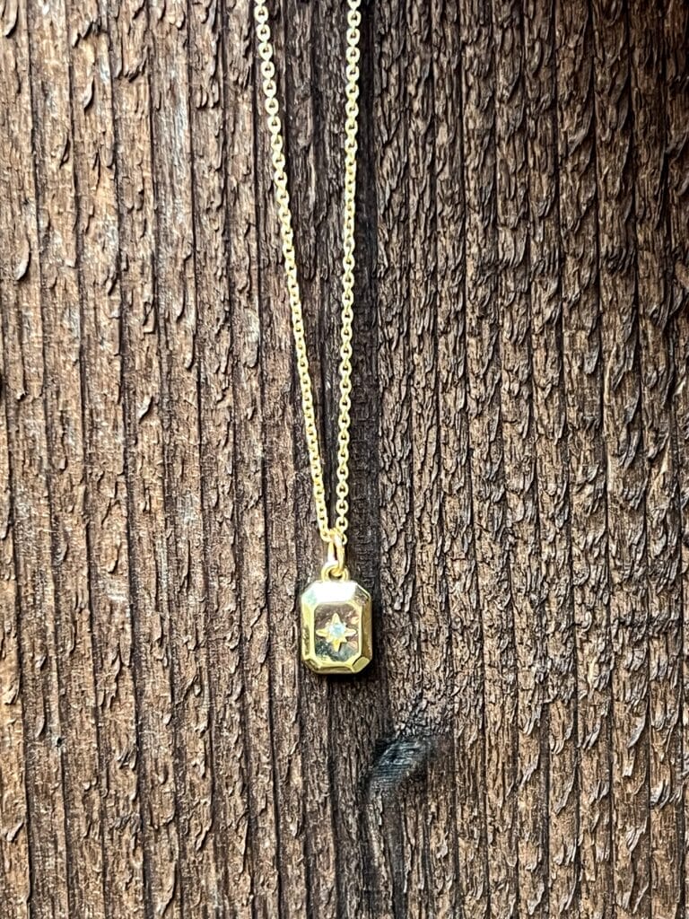 gold and crystal necklace against a wood background
