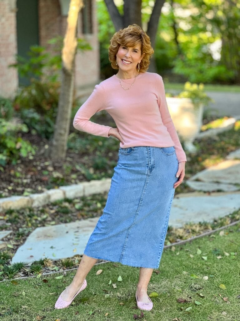 woman wearing pink crewneck sweater and pink ballet flats with long denim skirt