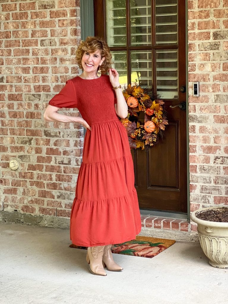 woman wearing rust midi dress and cowboy boots standing by a back door