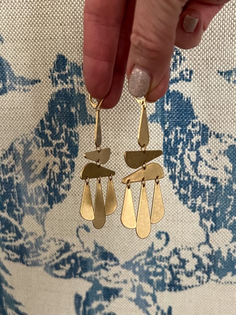 gold statement earrings up against a blue and white fabric
