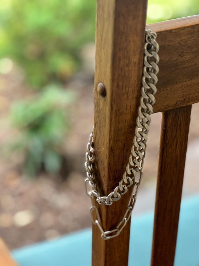 cabi id necklace in silver hanging over the side of a chair