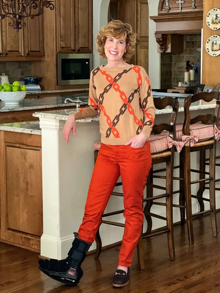 woman standing by bar in a kitchen wearing talbots chain link sweater and orange pants