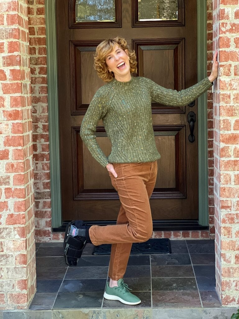 woman wearing boot standing by door wearing green sweater