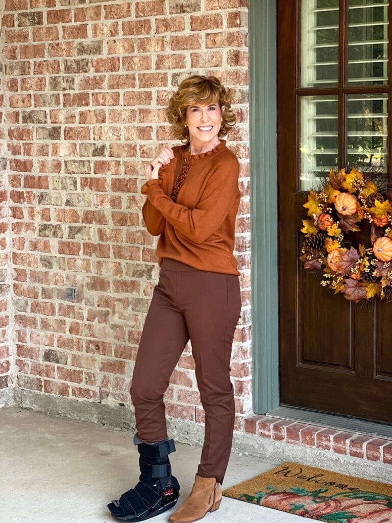 woman wearing brown amazon sweater standing by door with fall wreath