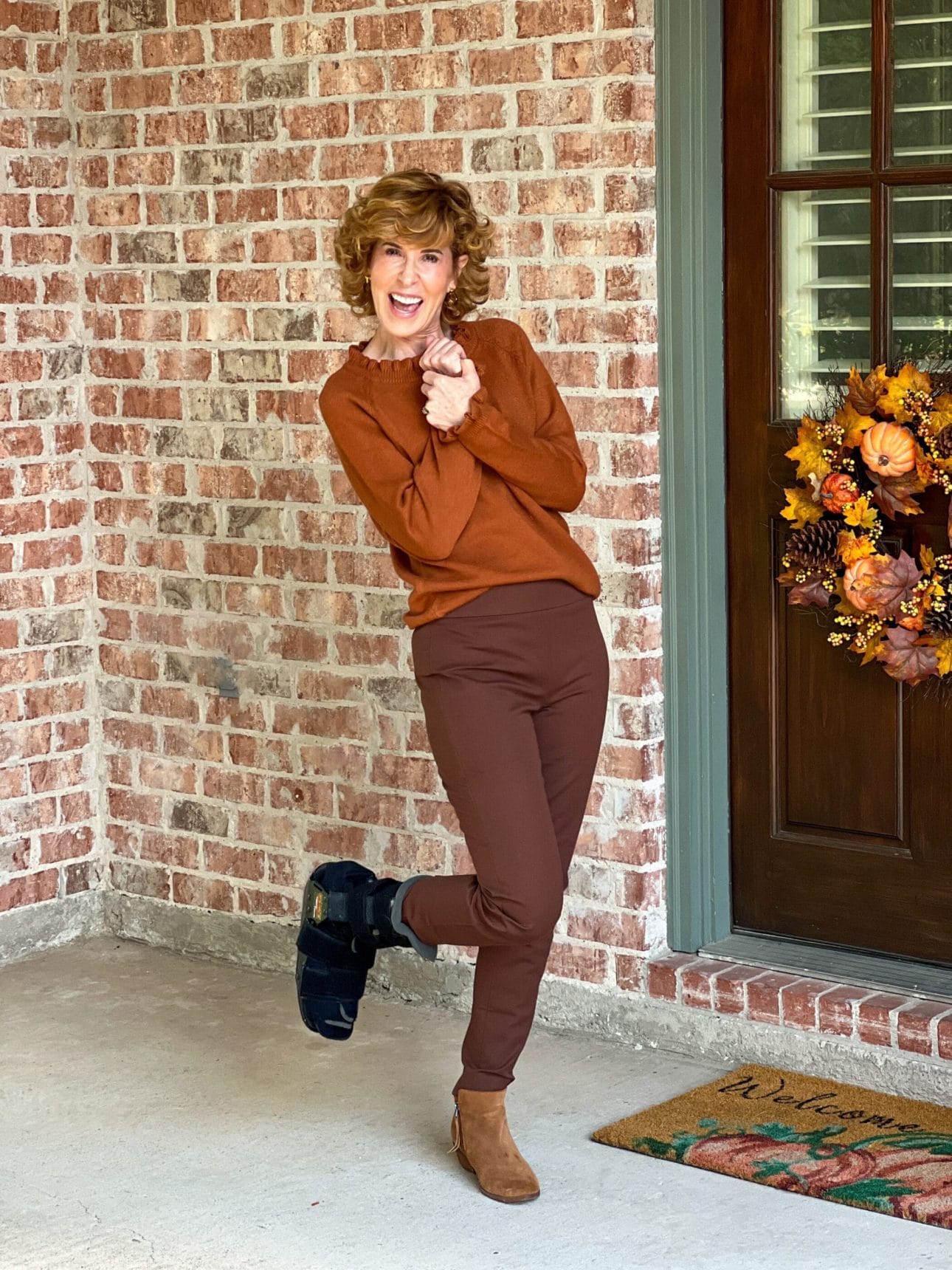 woman wearing brown amazon sweater standing by door with fall wreath