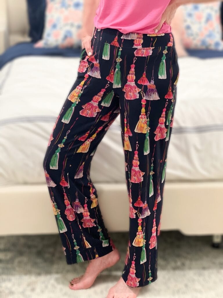 woman wearing pj pants with tassels on them standing in front of a bed