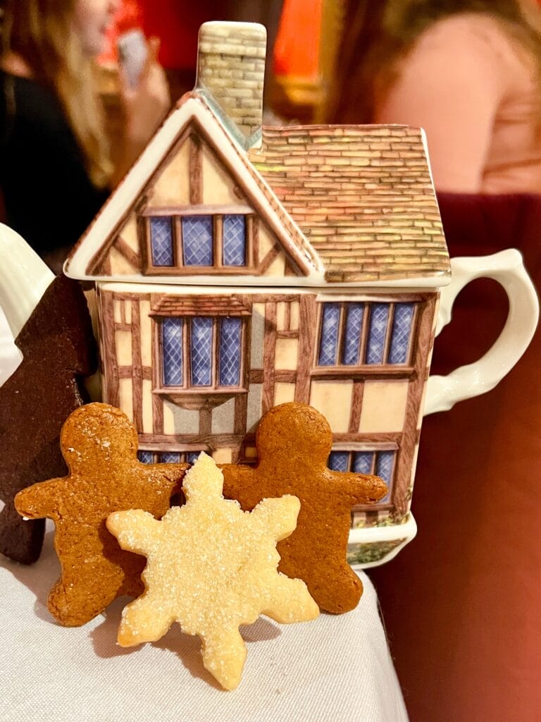 teapot shaped like a house and holiday cookies in front