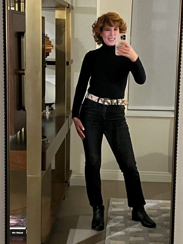 woman over 50 taking a selfie of her all black outfit with burberry belt