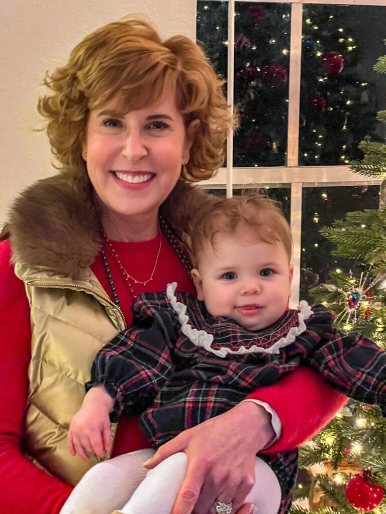 grandma with grandbaby standing in front of a christmas tree