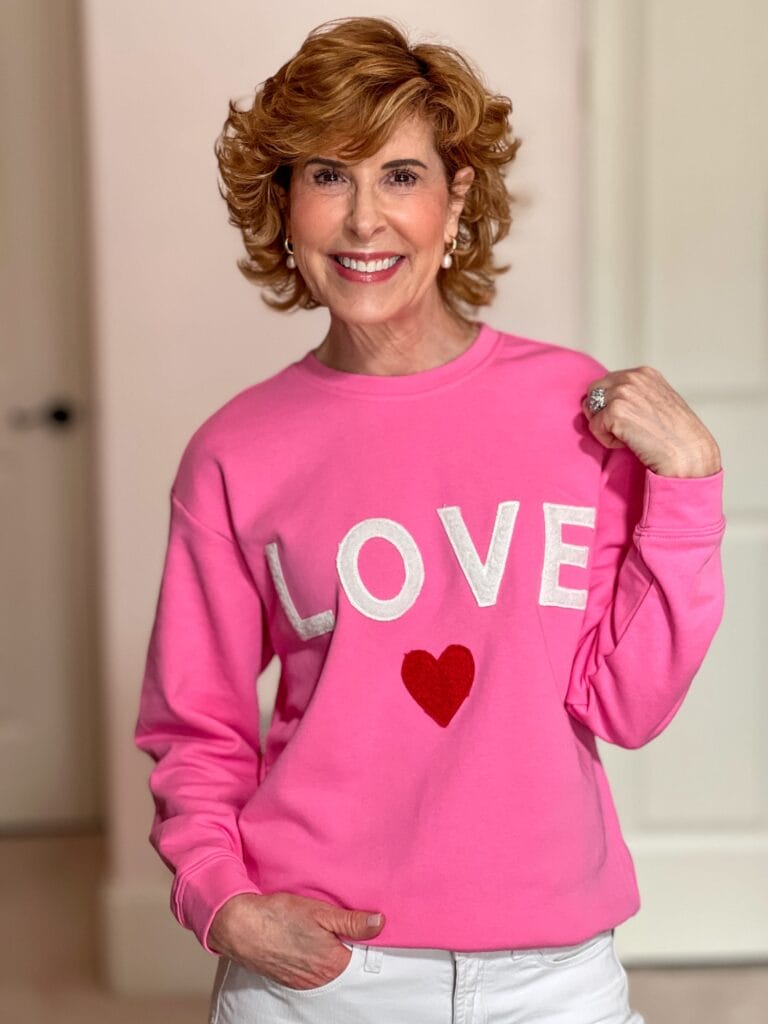 Woman over 50 wearing pink Avara LOVE sweatshirt.