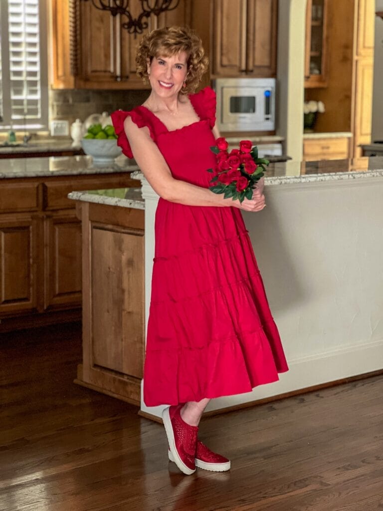woman wearing red hill house home nap dress standing in house holding red roses