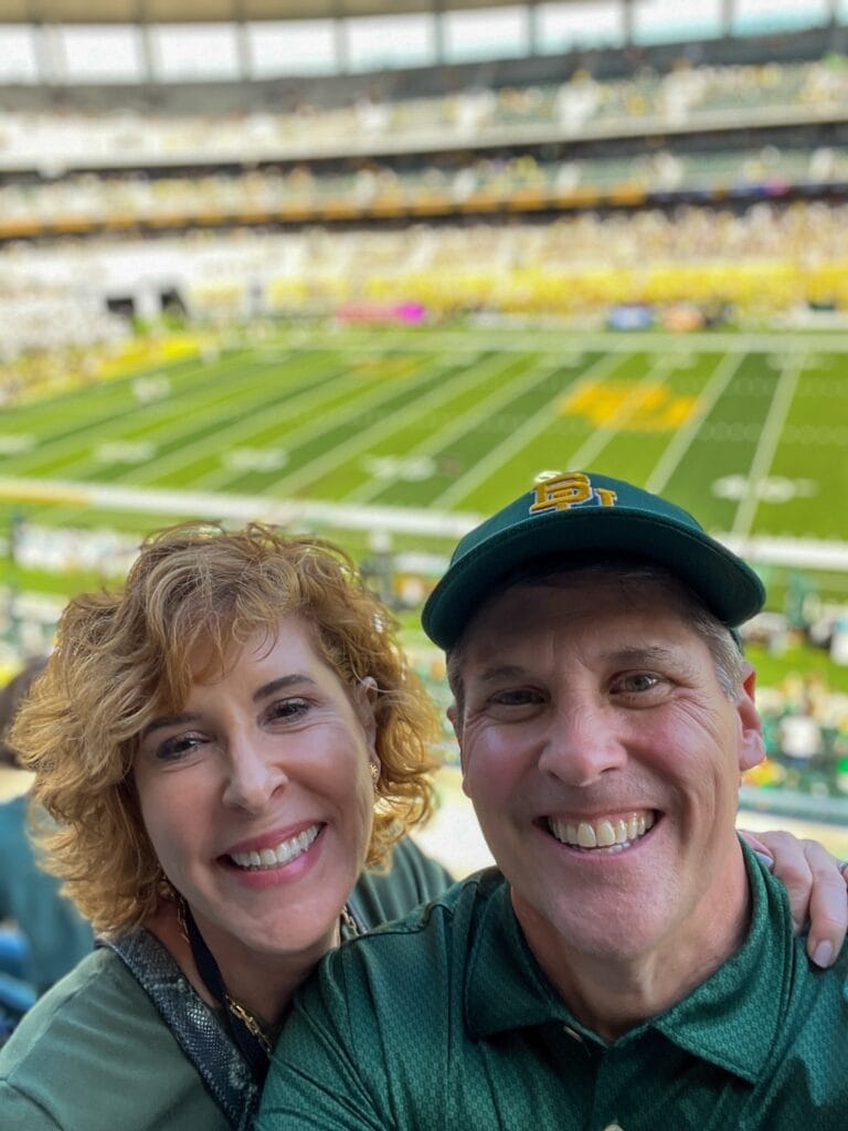 couple at a baylor football game with the field in the background