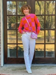woman wearing pink and orange sweater from avara standing in front of french doors