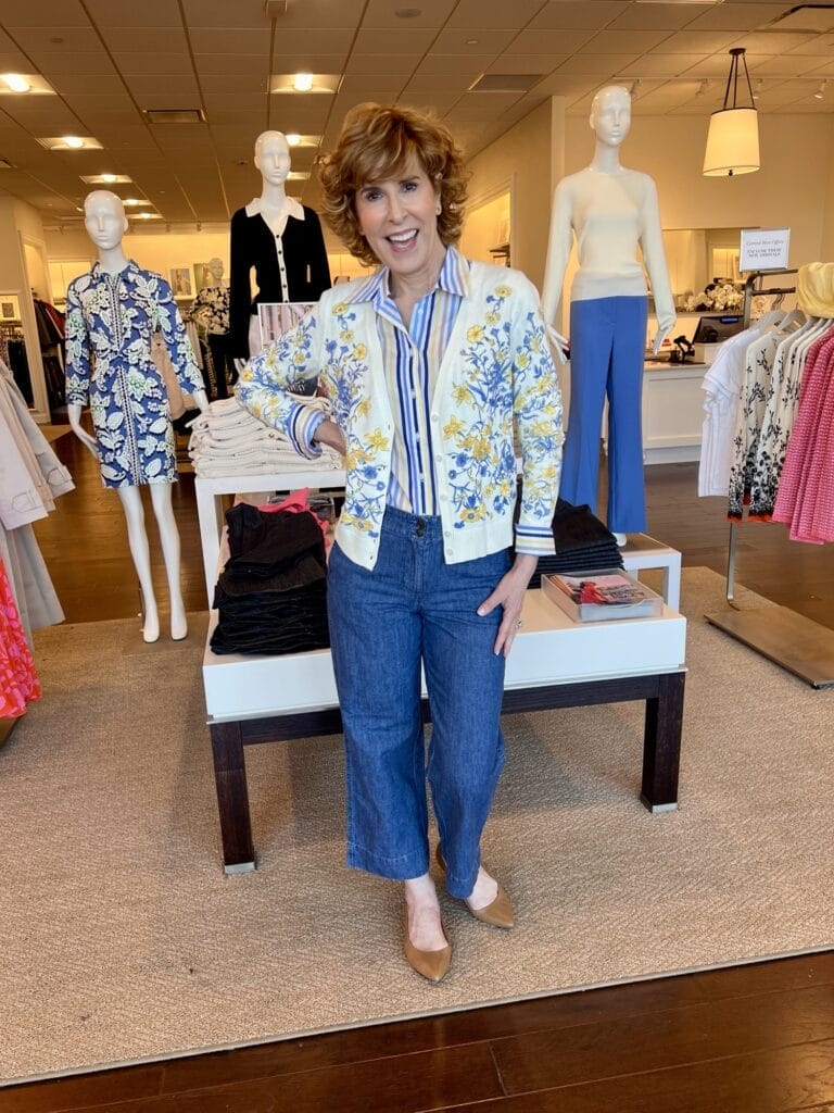 woman wearing striped button down from talbots with cardigan and jeans standing in talbots store