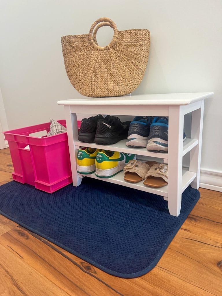 shoe bench on navy blue mat with pink plastic crate beside