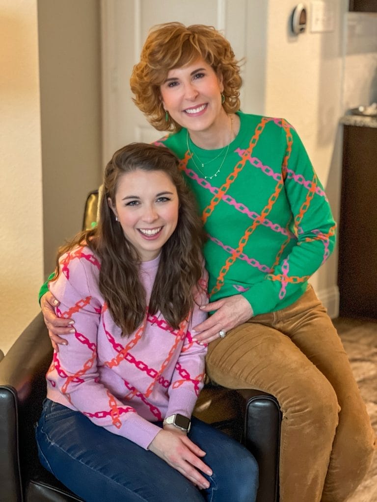 woman over 50 sitting with her daughter in law wearing coordinating sweaters