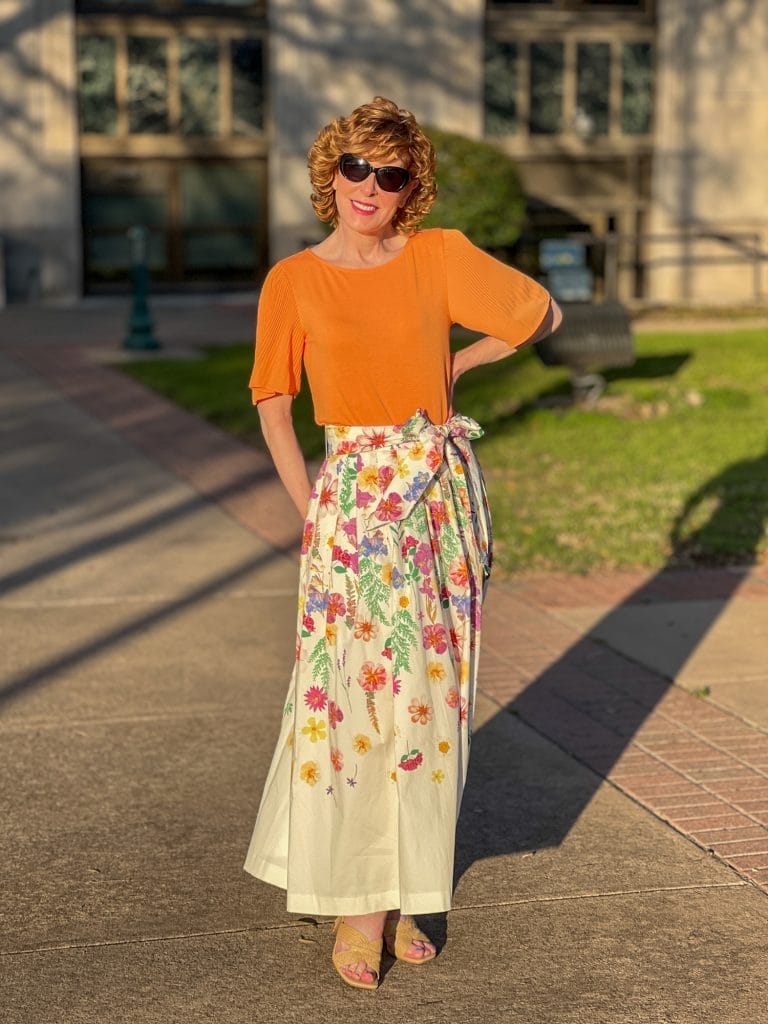 woman wearing floral skirt and orange top at sunset