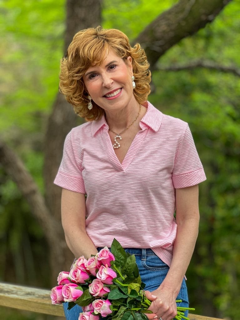 woman holding pink roses wearing a pink johnny collar tee from talbots