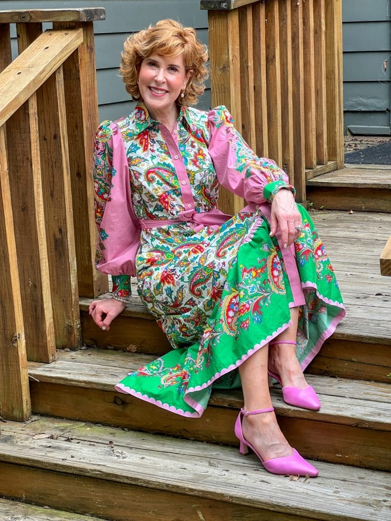 woman over 50 sitting on staircase wearing print dress in bright colors